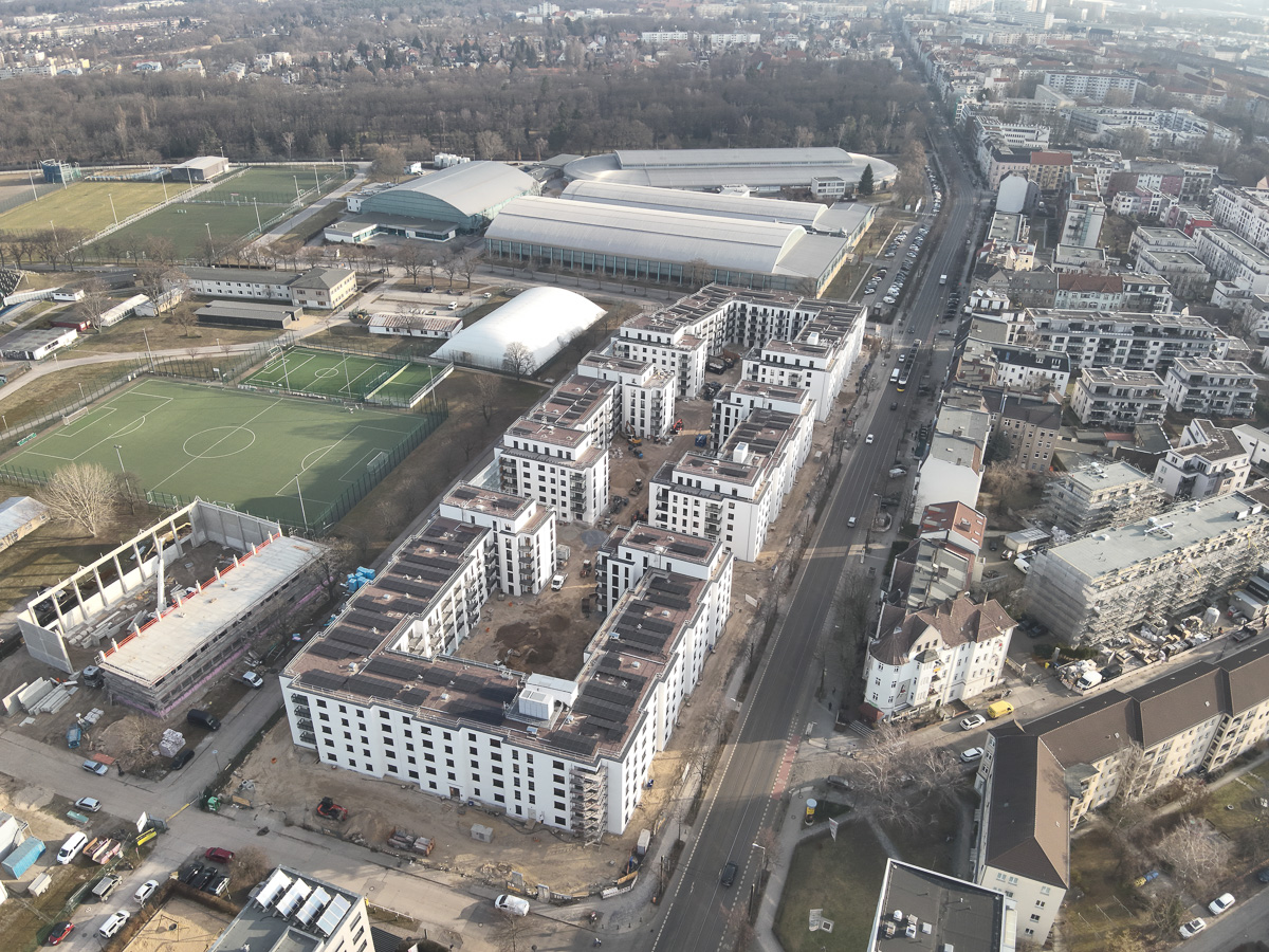 Drohnenaufnahme eines Neubau-Wohnquartiers mit installierter Photovoltaikanlage auf den Flachdächern der Mehrfamilienhäuser. Das Projekt zeigt die professionelle Umsetzung einer großflächigen PV-Anlage zur nachhaltigen Stromerzeugung im urbanen Wohnungsbau. Die Solarmodule wurden auf mehreren Gebäuden montiert und tragen zur CO₂-Reduzierung sowie zur Energieeffizienz moderner Wohnanlagen bei.