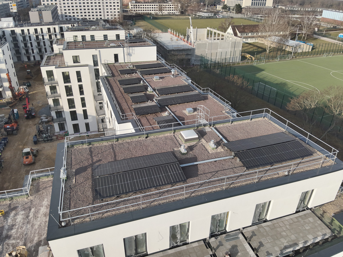 Neubau-Wohnquartiers mit installierter Photovoltaikanlage auf den Flachdächern der Mehrfamilienhäuser. Das Projekt zeigt die professionelle Umsetzung einer großflächigen PV-Anlage zur nachhaltigen Stromerzeugung im urbanen Wohnungsbau. Die Solarmodule wurden auf mehreren Gebäuden montiert und tragen zur CO₂-Reduzierung sowie zur Energieeffizienz moderner Wohnanlagen bei.