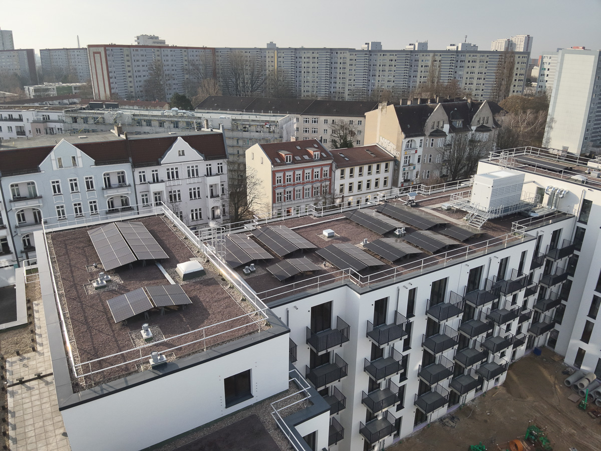 Neubau-Wohnquartiers mit installierter Photovoltaikanlage auf den Flachdächern der Mehrfamilienhäuser. Das Projekt zeigt die professionelle Umsetzung einer großflächigen PV-Anlage zur nachhaltigen Stromerzeugung im urbanen Wohnungsbau. Die Solarmodule wurden auf mehreren Gebäuden montiert und tragen zur CO₂-Reduzierung sowie zur Energieeffizienz moderner Wohnanlagen bei.