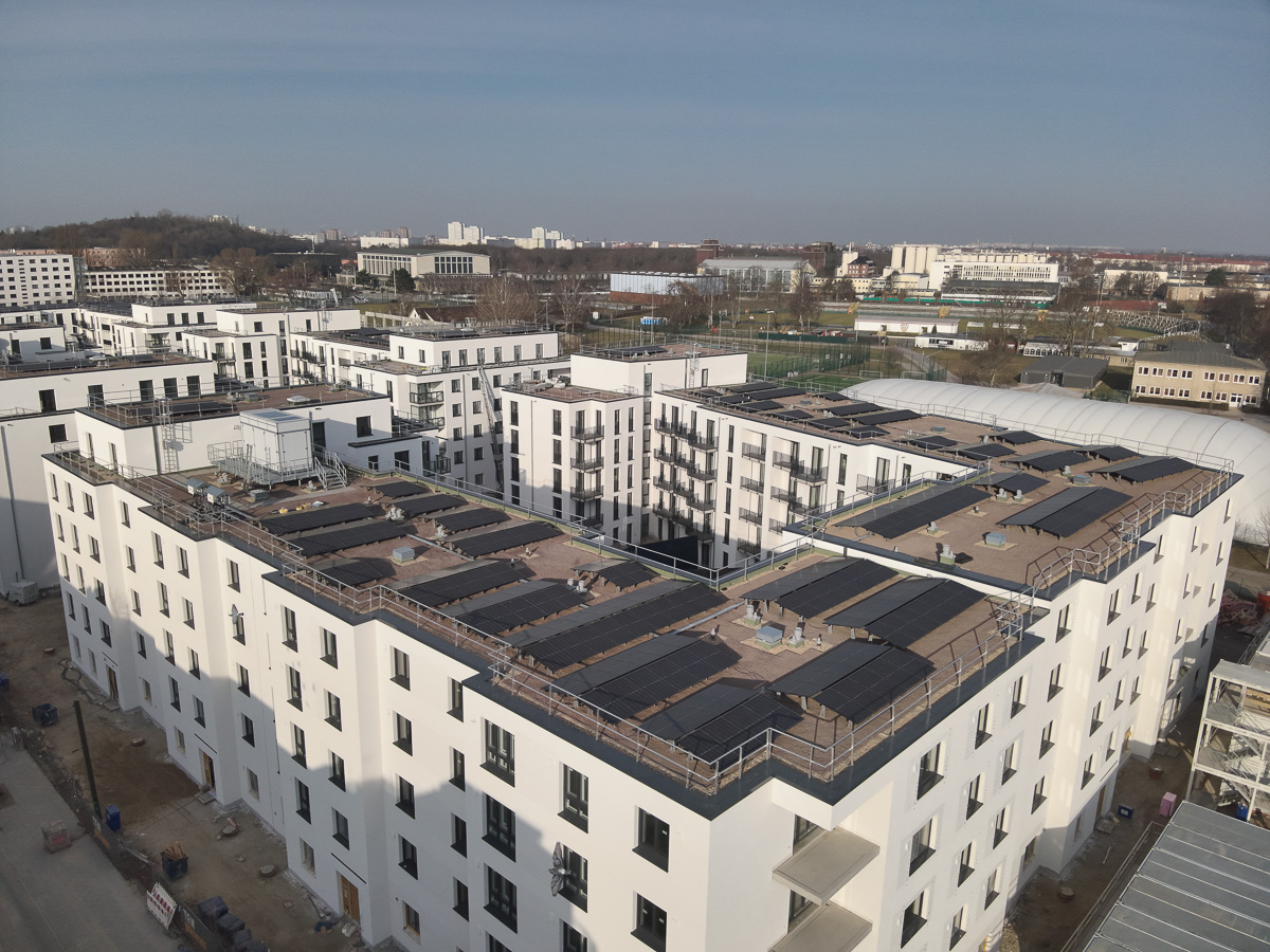 Neubau-Wohnquartiers mit installierter Photovoltaikanlage auf den Flachdächern der Mehrfamilienhäuser. Das Projekt zeigt die professionelle Umsetzung einer großflächigen PV-Anlage zur nachhaltigen Stromerzeugung im urbanen Wohnungsbau. Die Solarmodule wurden auf mehreren Gebäuden montiert und tragen zur CO₂-Reduzierung sowie zur Energieeffizienz moderner Wohnanlagen bei.