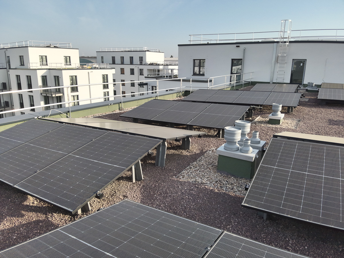 Neubau-Wohnquartiers mit installierter Photovoltaikanlage auf den Flachdächern der Mehrfamilienhäuser. Das Projekt zeigt die professionelle Umsetzung einer großflächigen PV-Anlage zur nachhaltigen Stromerzeugung im urbanen Wohnungsbau. Die Solarmodule wurden auf mehreren Gebäuden montiert und tragen zur CO₂-Reduzierung sowie zur Energieeffizienz moderner Wohnanlagen bei.
