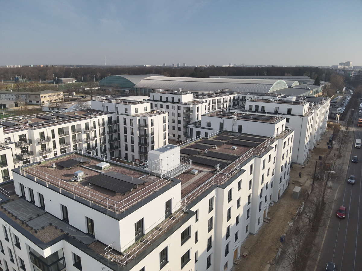 Neubau-Wohnquartiers mit installierter Photovoltaikanlage auf den Flachdächern der Mehrfamilienhäuser. Das Projekt zeigt die professionelle Umsetzung einer großflächigen PV-Anlage zur nachhaltigen Stromerzeugung im urbanen Wohnungsbau. Die Solarmodule wurden auf mehreren Gebäuden montiert und tragen zur CO₂-Reduzierung sowie zur Energieeffizienz moderner Wohnanlagen bei.