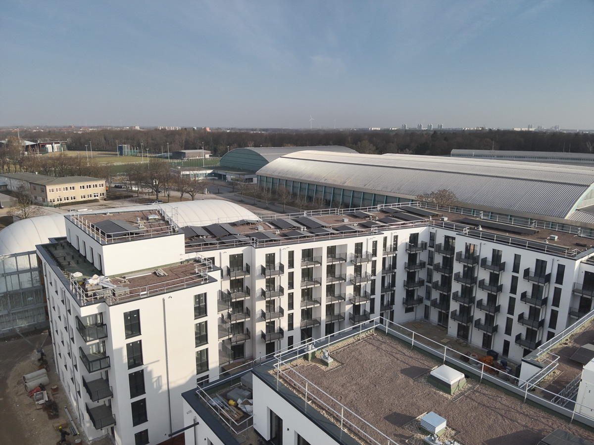 Neubau-Wohnquartiers mit installierter Photovoltaikanlage auf den Flachdächern der Mehrfamilienhäuser. Das Projekt zeigt die professionelle Umsetzung einer großflächigen PV-Anlage zur nachhaltigen Stromerzeugung im urbanen Wohnungsbau. Die Solarmodule wurden auf mehreren Gebäuden montiert und tragen zur CO₂-Reduzierung sowie zur Energieeffizienz moderner Wohnanlagen bei.
