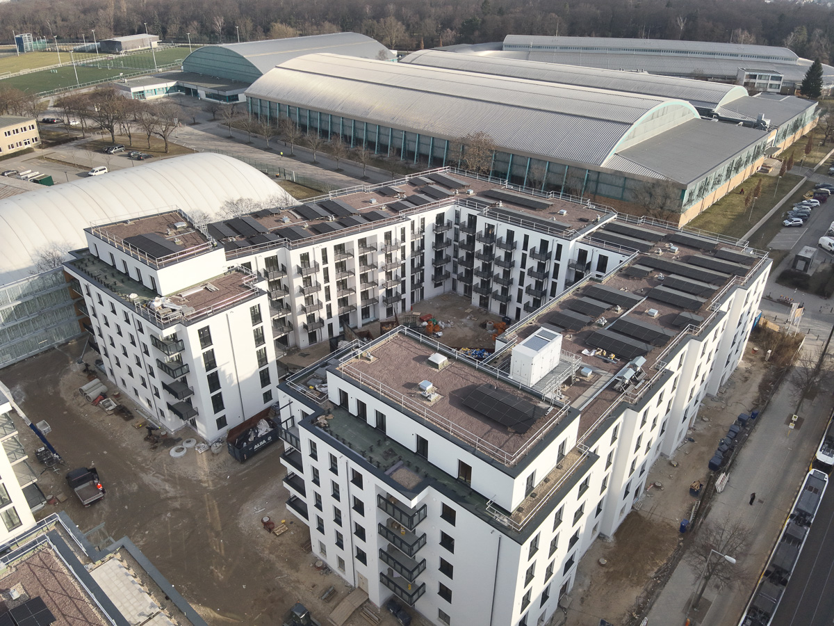 Neubau-Wohnquartiers mit installierter Photovoltaikanlage auf den Flachdächern der Mehrfamilienhäuser. Das Projekt zeigt die professionelle Umsetzung einer großflächigen PV-Anlage zur nachhaltigen Stromerzeugung im urbanen Wohnungsbau. Die Solarmodule wurden auf mehreren Gebäuden montiert und tragen zur CO₂-Reduzierung sowie zur Energieeffizienz moderner Wohnanlagen bei.