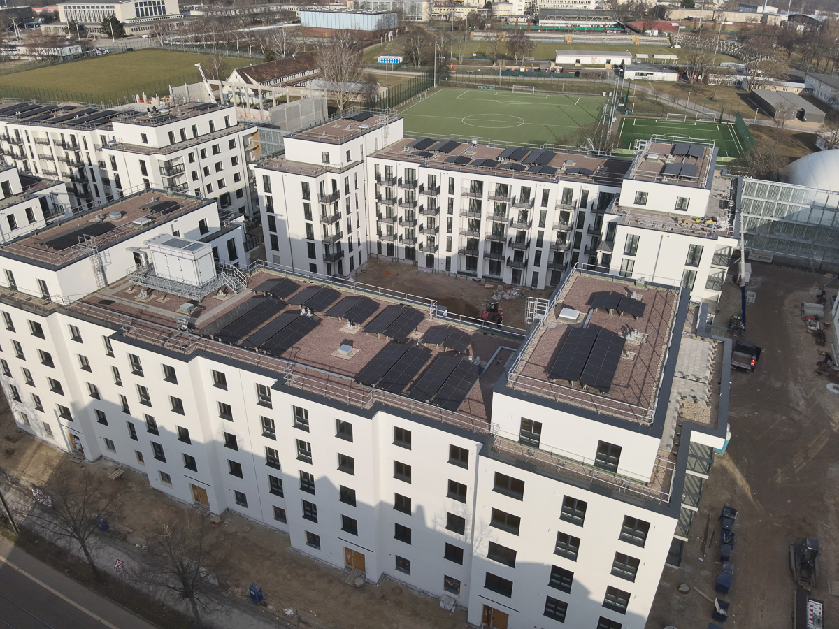 Neubau-Wohnquartiers mit installierter Photovoltaikanlage auf den Flachdächern der Mehrfamilienhäuser. Das Projekt zeigt die professionelle Umsetzung einer großflächigen PV-Anlage zur nachhaltigen Stromerzeugung im urbanen Wohnungsbau. Die Solarmodule wurden auf mehreren Gebäuden montiert und tragen zur CO₂-Reduzierung sowie zur Energieeffizienz moderner Wohnanlagen bei.