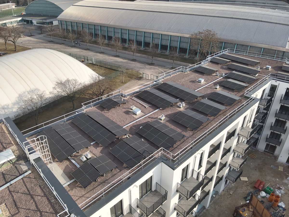 Neubau-Wohnquartiers mit installierter Photovoltaikanlage auf den Flachdächern der Mehrfamilienhäuser. Das Projekt zeigt die professionelle Umsetzung einer großflächigen PV-Anlage zur nachhaltigen Stromerzeugung im urbanen Wohnungsbau. Die Solarmodule wurden auf mehreren Gebäuden montiert und tragen zur CO₂-Reduzierung sowie zur Energieeffizienz moderner Wohnanlagen bei.
