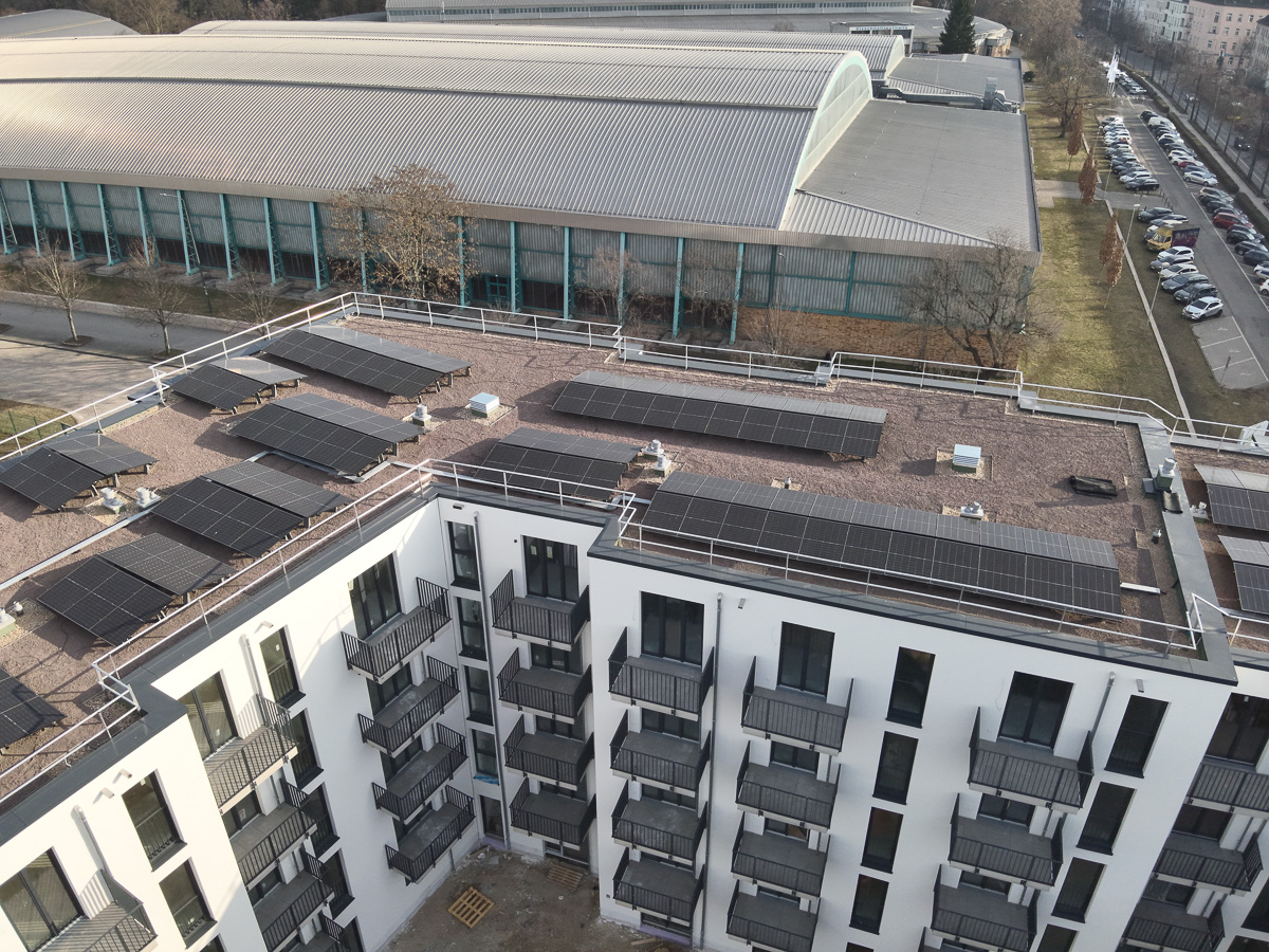 Neubau-Wohnquartiers mit installierter Photovoltaikanlage auf den Flachdächern der Mehrfamilienhäuser. Das Projekt zeigt die professionelle Umsetzung einer großflächigen PV-Anlage zur nachhaltigen Stromerzeugung im urbanen Wohnungsbau. Die Solarmodule wurden auf mehreren Gebäuden montiert und tragen zur CO₂-Reduzierung sowie zur Energieeffizienz moderner Wohnanlagen bei.